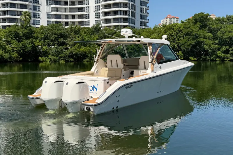 Slide: The Image of 2016 Pursuit DC 325 Dual Console boat on calm water near modern buildings. - 6