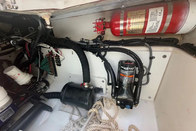 Slide: The Image of 2016 Pursuit DC 325 Dual Console engine compartment with fire extinguisher and hydraulic steering system. - 58