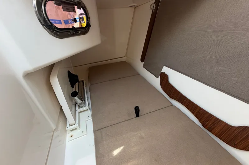 Slide: The Image of Interior cabin of 2016 Pursuit DC 325 Dual Console boat, featuring beige upholstery and wood accents. - 47