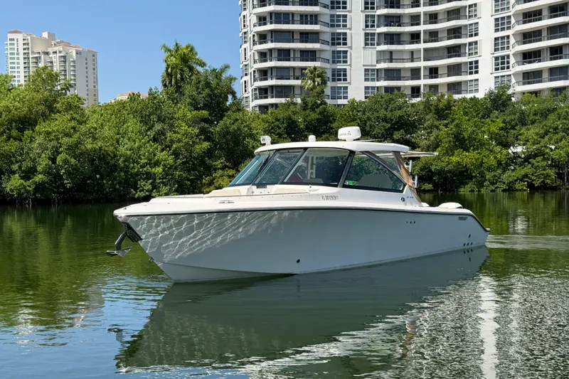 Slide: The Image of 2016 Pursuit DC 325 Dual Console boat on calm water, with modern buildings in the background. - 4
