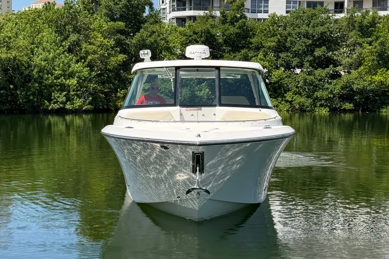 Slide: The Image of 2016 Pursuit DC 325 Dual Console boat on calm water, surrounded by lush greenery. - 8