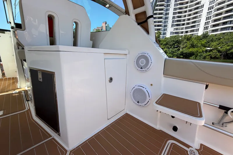 Slide: The Image of 2016 Pursuit DC 325 Dual Console interior with seating and speakers, docked near high-rise buildings. - 21