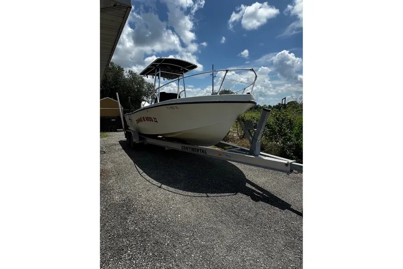 Slide: The Image of 1977 Mako 235 boat on trailer under a partly cloudy sky. - 1