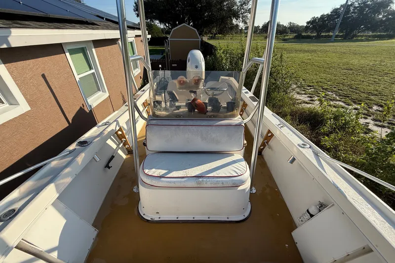 Slide: The Image of 1977 Mako 235 boat interior with console and seating, parked outdoors near a house. - 15