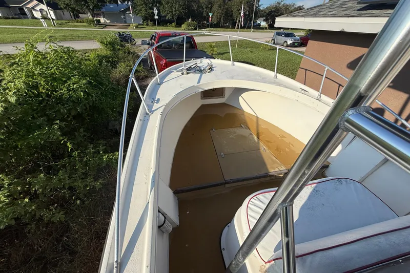 Slide: The Image of 1977 Mako 235 boat with open deck, parked near greenery and a red truck. - 30