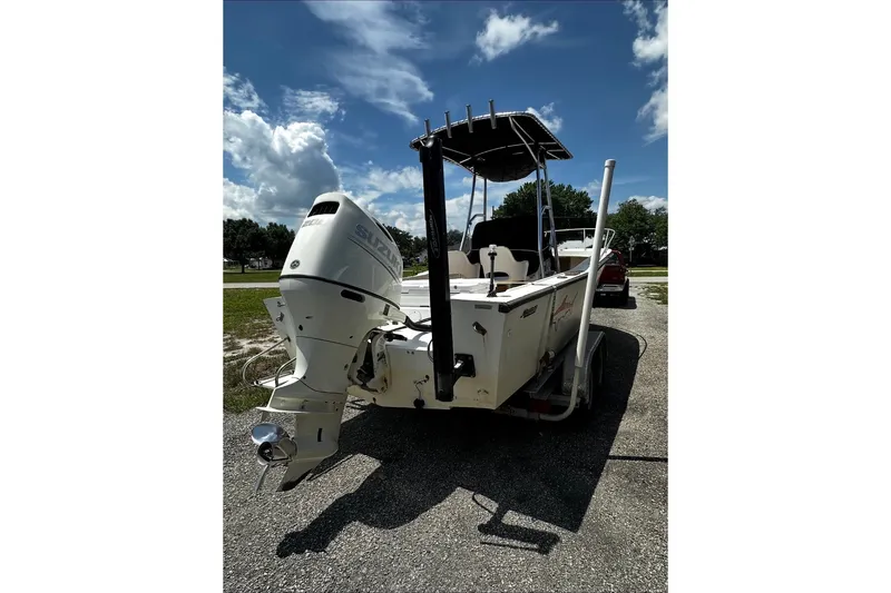 Slide: The Image of 1977 Mako 235 boat with Suzuki outboard motor on a trailer under a blue sky. - 2