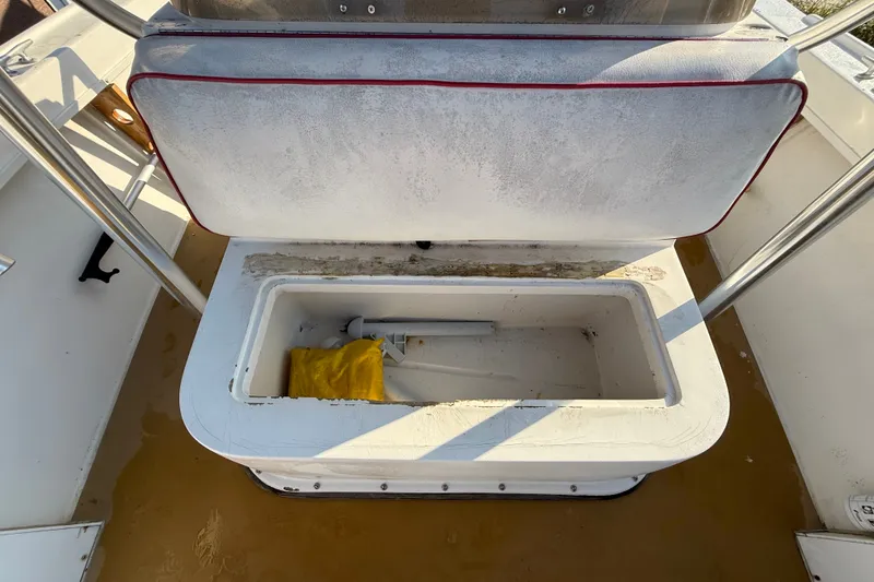 Slide: The Image of Open storage compartment on a 1977 Mako 235 boat, featuring a yellow item inside. - 16