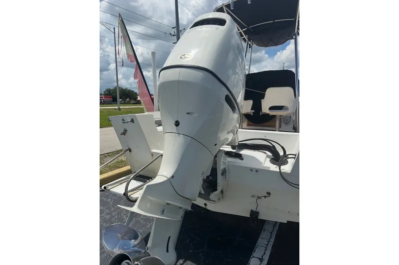 Slide: The Image of 1977 Mako 235 boat with outboard motor, parked outdoors under cloudy sky. - 6