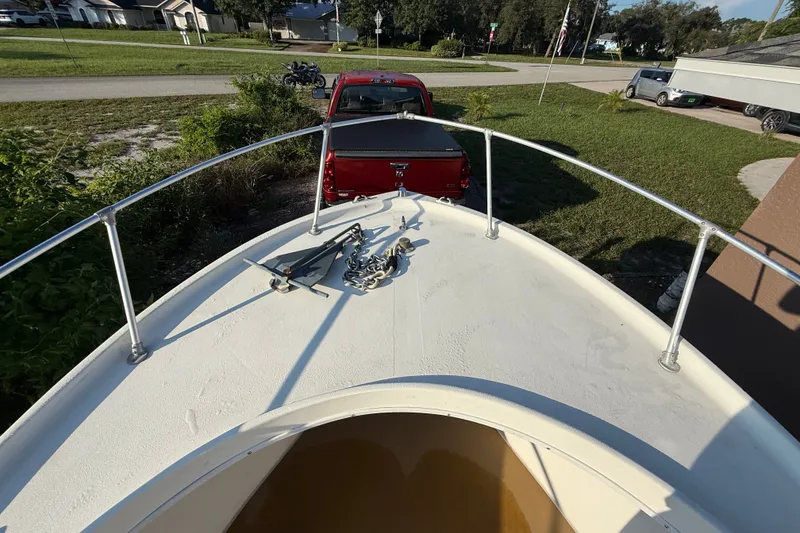Slide: The Image of 1977 Mako 235 boat bow with anchor, parked near red truck in residential area. - 36