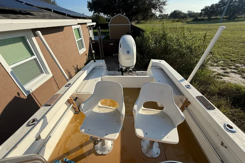 Slide: The Image of 1977 Mako 235 boat with dual seats and outboard motor in a backyard setting. - 19