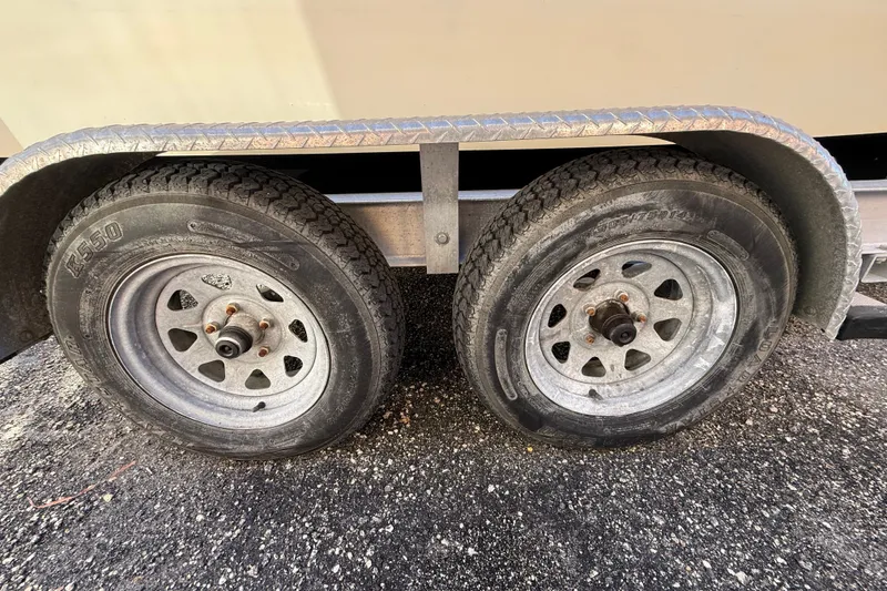 Slide: The Image of Trailer wheels of a 1977 Mako 235 boat on asphalt surface. - 41