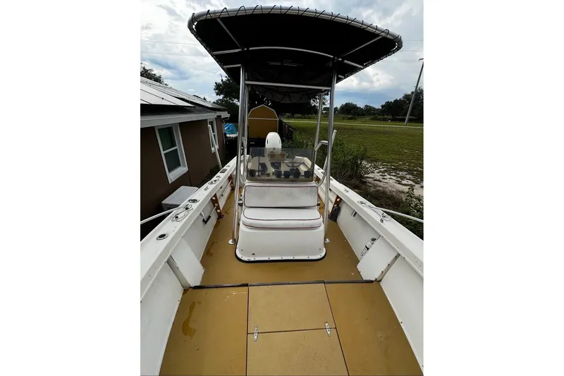 Slide: The Image of 1977 Mako 235 boat with canopy, viewed from deck, near house and greenery. - 5