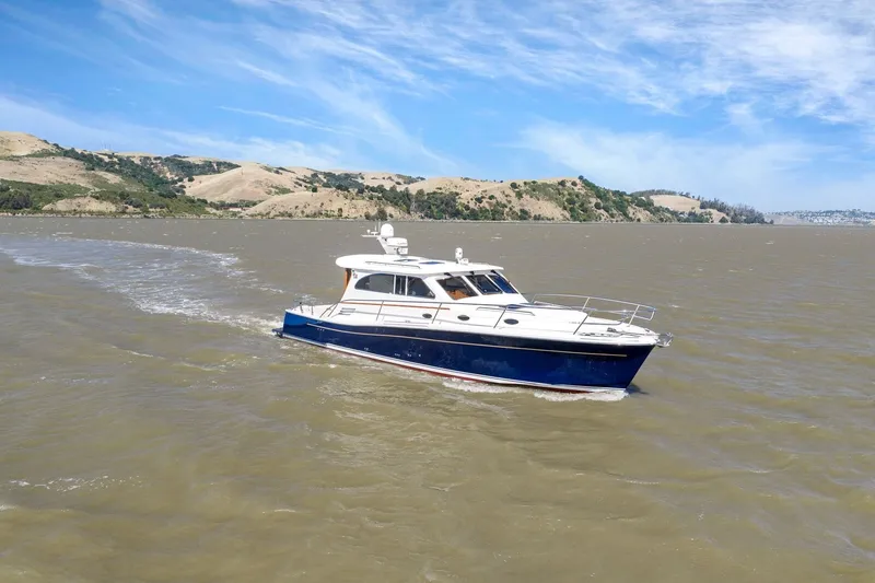 Slide: The Image of 2009 Rivolta Coupe 4.5 yacht cruising on a scenic lake under a clear blue sky. - 16