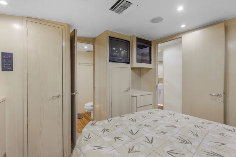 Slide: The Image of 1998 Hatteras 60 Convertible yacht bedroom with TV, light wood cabinetry, and patterned bedding. - 20
