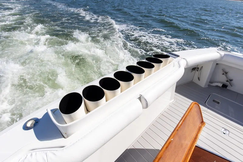Slide: The Image of 1998 Hatteras 60 Convertible yacht deck with rod holders, cruising on open water. - 27