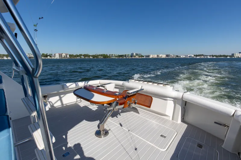 Slide: The Image of 1998 Hatteras 60 Convertible yacht cruising on open water, clear sky, cityscape in background. - 25