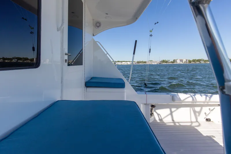 Slide: The Image of 1998 Hatteras 60 Convertible yacht deck with blue cushions, overlooking calm waters. - 28