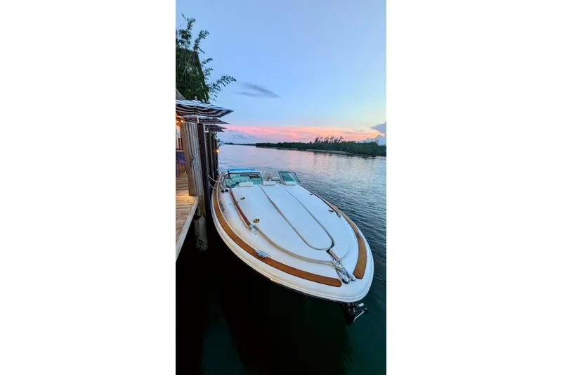 The Image of 2013 Chris-Craft Corsair 32 docked at sunset, showcasing elegant design and serene waters. - 2