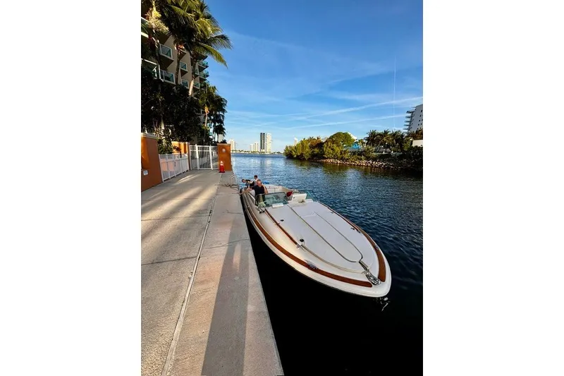 Slide: The Image of 2013 Chris-Craft Corsair 32 docked by a scenic waterfront with palm trees. - 3