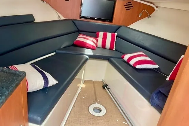 Slide: The Image of 2013 Chris-Craft Corsair 32 cabin interior with blue seating and striped pillows. - 9