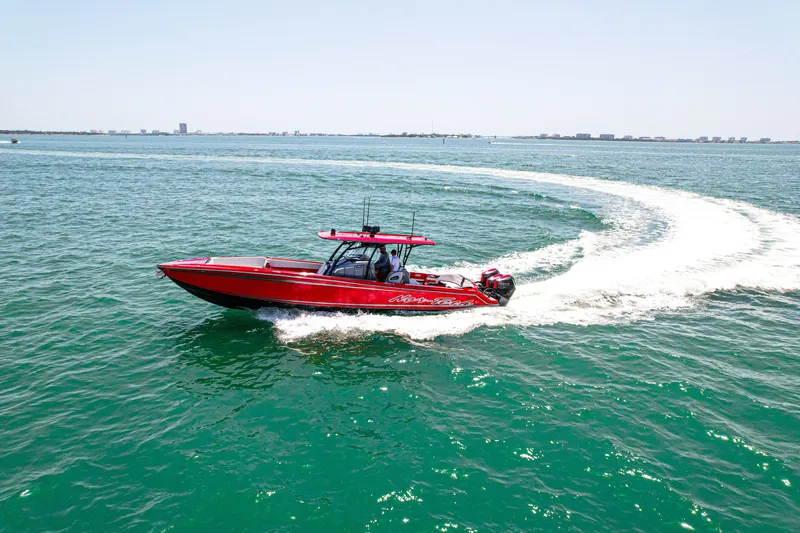 Slide: The Image of Red 2022 Nor-Tech 390 Sport boat cruising on open water, leaving a wake trail. - 24