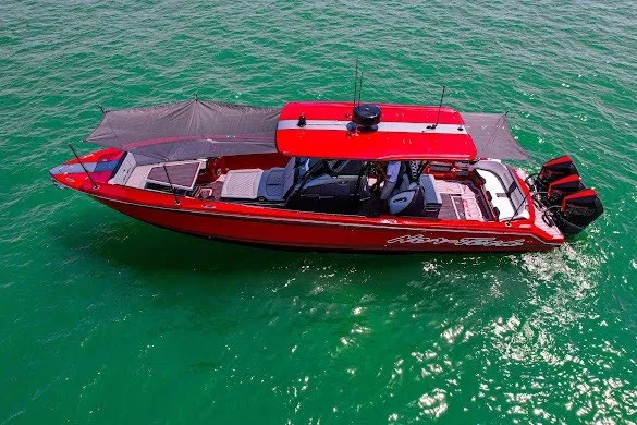 Slide: The Image of Red 2022 Nor-Tech 390 Sport boat cruising on clear turquoise water. - 18
