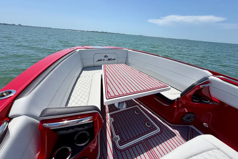 Slide: The Image of 2022 Nor-Tech 390 Sport boat interior with red and white seating, table, and ocean view. - 34