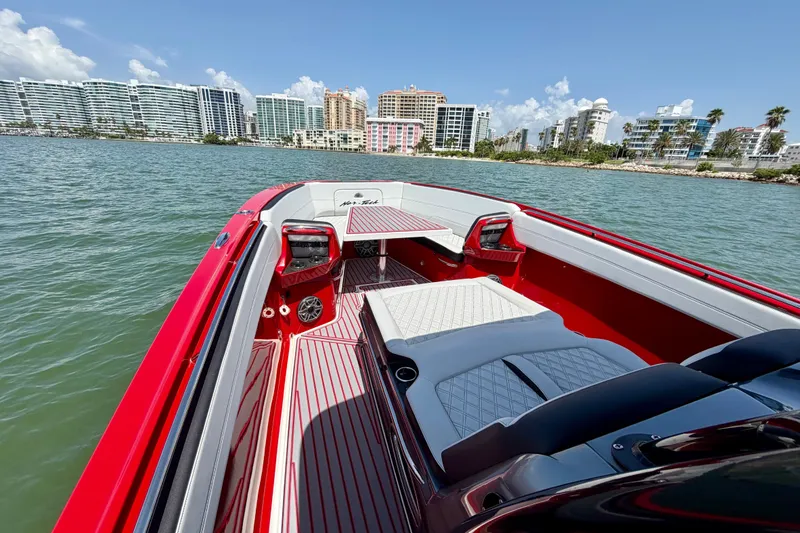 Slide: The Image of 2022 Nor-Tech 390 Sport boat with red interior, cruising near waterfront cityscape. - 31