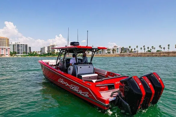 Slide: The Image of Red 2022 Nor-Tech 390 Sport boat cruising on water near city skyline. - 2