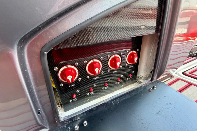 Slide: The Image of Control panel of a 2022 Nor-Tech 390 Sport boat with red switches. - 65