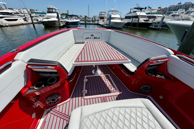 Slide: The Image of 2022 Nor-Tech 390 Sport boat interior with red and white seating, docked at a marina. - 36