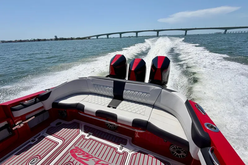 Slide: The Image of 2022 Nor-Tech 390 Sport boat cruising on water with triple engines, bridge in background. - 46