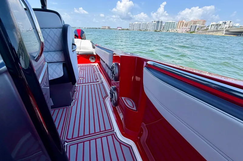 Slide: The Image of 2022 Nor-Tech 390 Sport boat interior with red accents, on a sunny day by the water. - 43