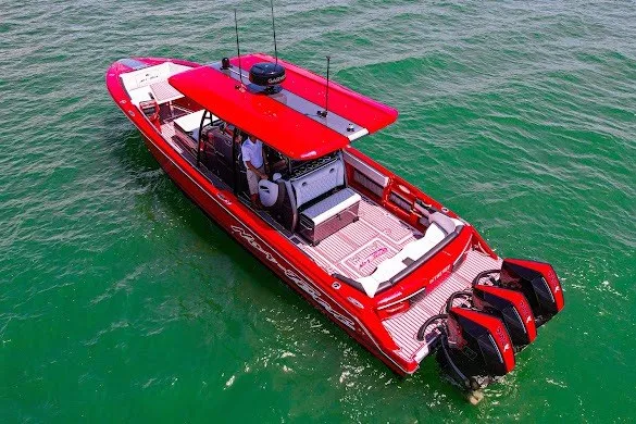 Slide: The Image of Red 2022 Nor-Tech 390 Sport boat cruising on clear green water. - 11