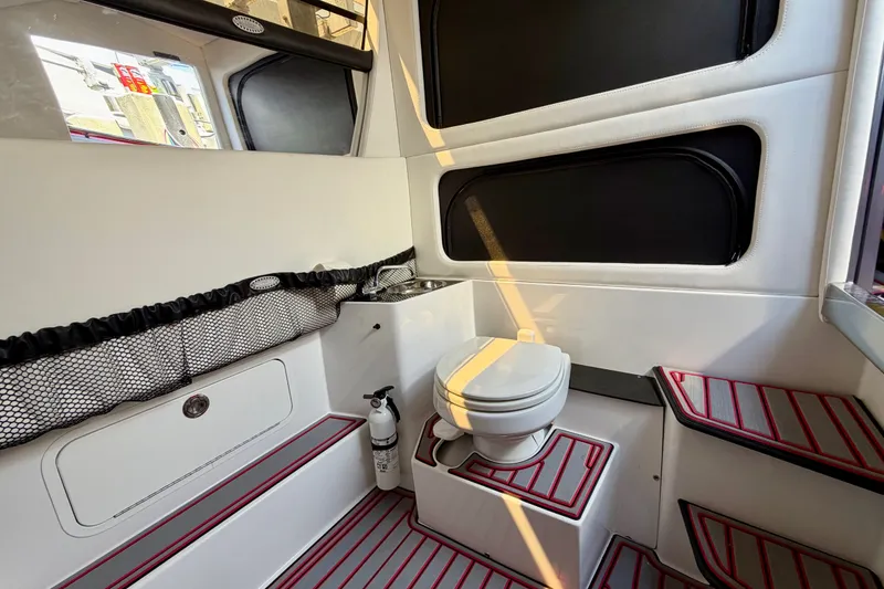 Slide: The Image of Interior of 2022 Nor-Tech 390 Sport boat featuring a compact bathroom with toilet and storage. - 61