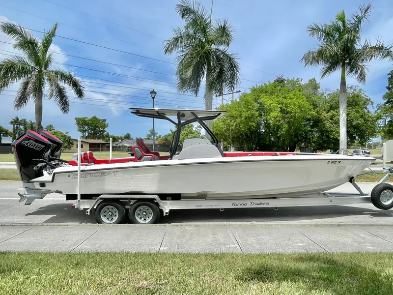 Slide: The Image of A white 32-foot boat on a trailer, surrounded by palm trees, with red seats and twin outboard engines. - 3