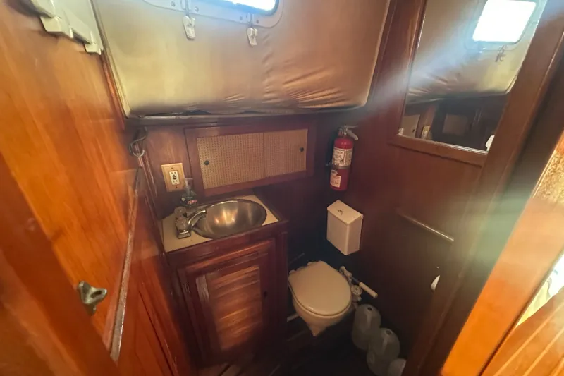 Slide: The Image of 1977 Down East Yachts DownEaster 45 yacht bathroom with sink, toilet, and wooden cabinetry. - 30