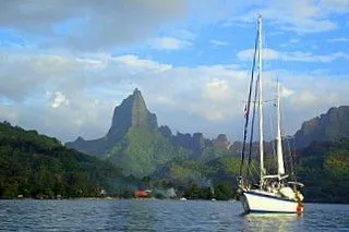 Slide: The Image of 1977 DownEaster 45 yacht sailing near lush mountainous landscape under a blue sky. - 2