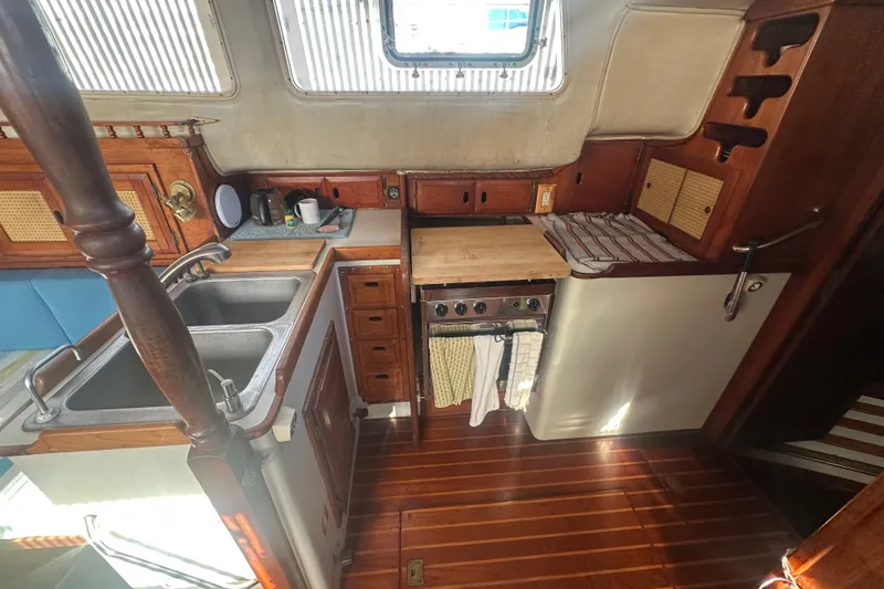 Slide: The Image of 1977 Down East Yachts DownEaster 45 galley with wooden cabinetry, dual sinks, and stove. - 24