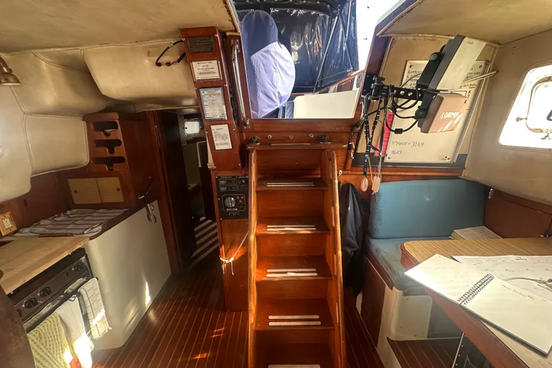 Slide: The Image of Interior of a 1977 Down East Yachts DownEaster 45 sailboat, featuring wooden stairs and cozy seating. - 23