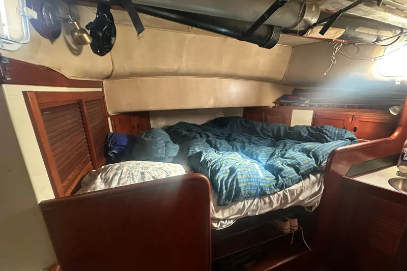Slide: The Image of The cabin of a 1977 DownEaster 45 with a cozy bed and wood paneling. - 27