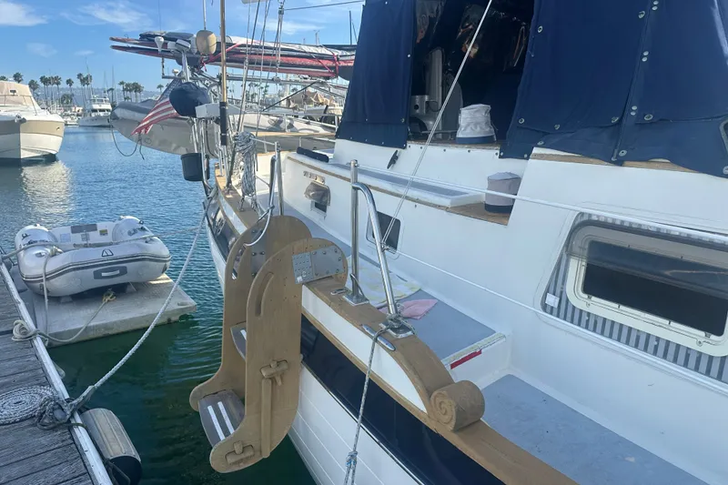 Slide: The Image of 1977 Down East Yachts DownEaster 45 sailboat docked with dinghy, blue canopy, and wooden ladder. - 17