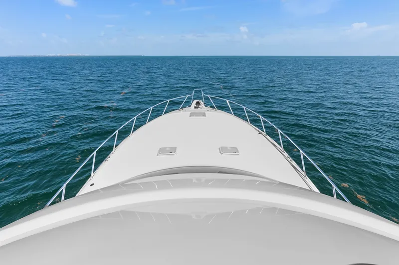 Slide: The Image of Bow view of 2017 Hatteras GT54 yacht cruising on open sea under clear blue sky. - 31