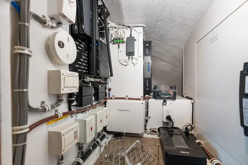 Slide: The Image of Electrical control room of a 2017 Hatteras GT54 yacht, featuring various equipment and wiring. - 75