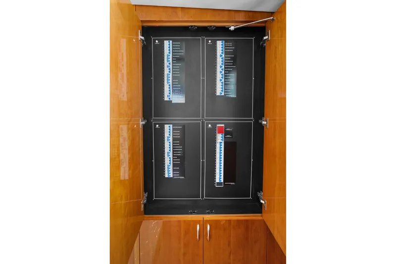 Slide: The Image of Electrical panel inside 2017 Hatteras GT54 yacht, featuring wooden cabinetry and circuit breakers. - 74