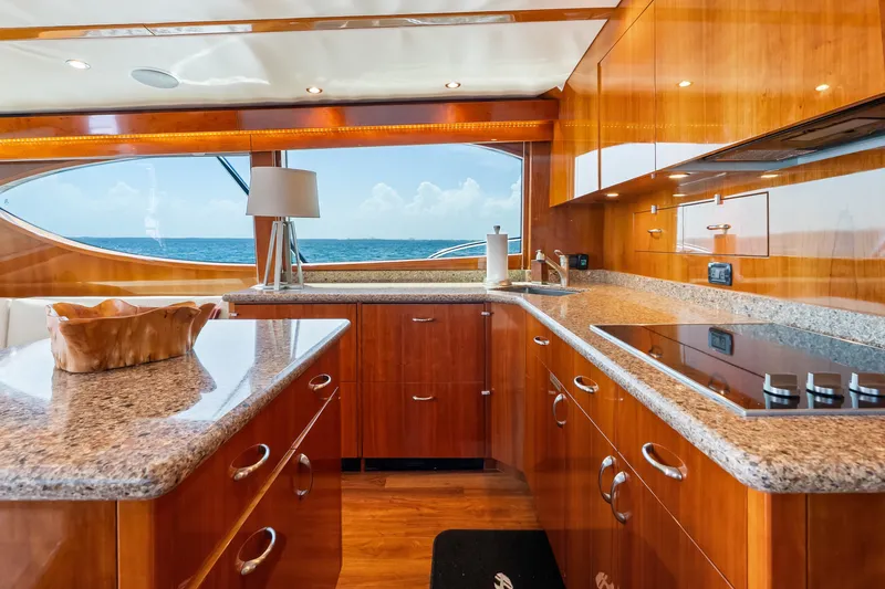 Slide: The Image of Luxurious 2017 Hatteras GT54 yacht kitchen with ocean view, featuring sleek wood cabinetry and granite countertops. - 45