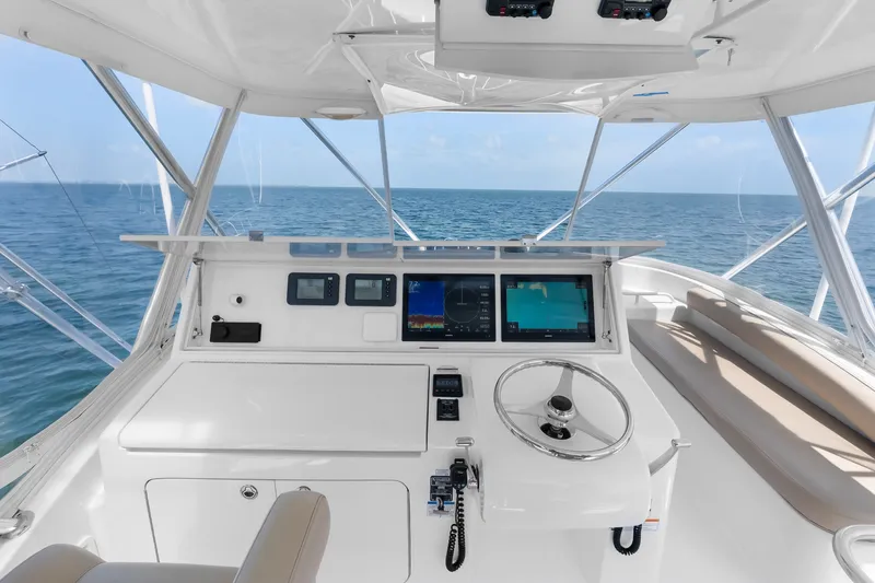 Slide: The Image of 2017 Hatteras GT54 helm with navigation screens, steering wheel, and ocean view. - 21