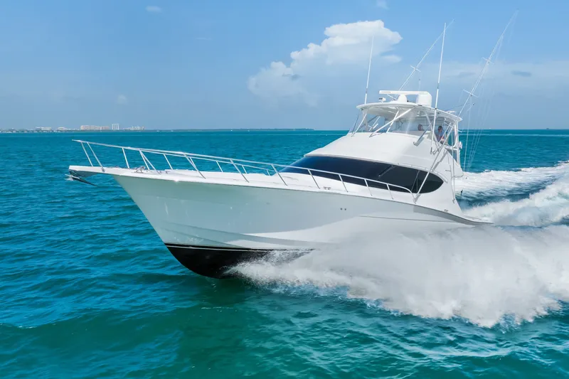 Slide: The Image of 2017 Hatteras GT54 yacht cruising on clear blue ocean waters. - 16