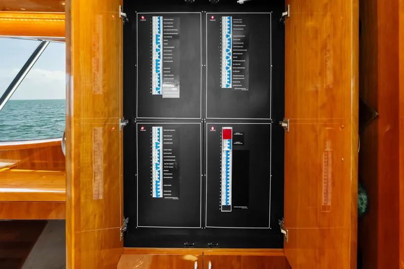 Slide: The Image of Electrical panel inside 2017 Hatteras GT54 yacht, featuring wooden cabinetry and ocean view. - 72