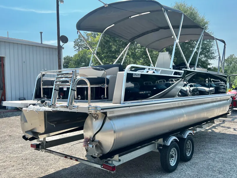 Slide: The Image of A modern pontoon boat with a gray sunshade and shiny aluminum hull sits on a trailer. - 3